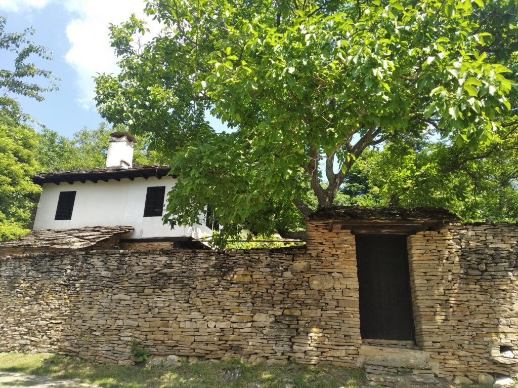 Традиционна възрожденска къща зад каменен зид и дървена порта по маршрута на екопътека „Иглика“ в село Иглика.