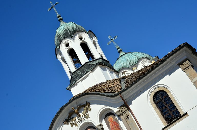 Куполи и камбанария на храм „Успение на Пресвета Богородица“ на фона на синьо небе